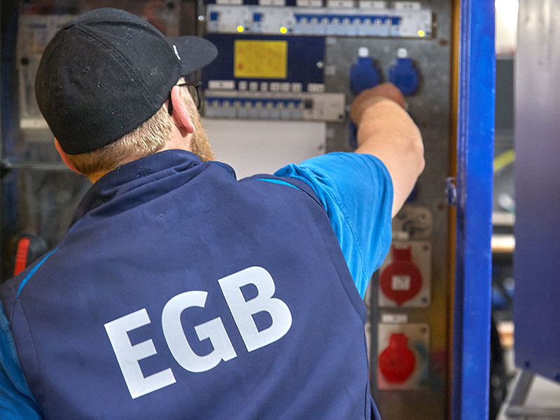 Ein Mitarbeiter von EGB steht an einem Stromverteilerkasten.